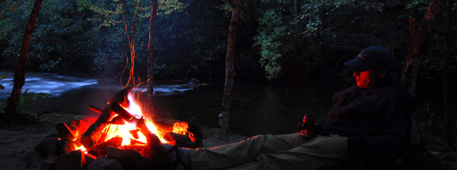 Fisherman sitting by camp fire on a Smoky Mountains Stream
